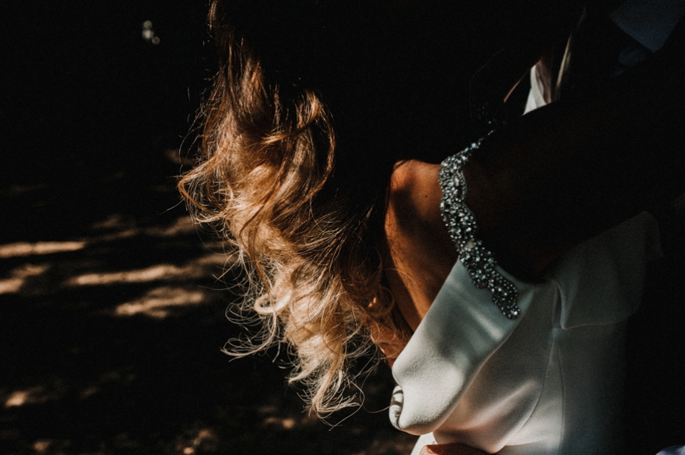 bride and groom enjoying a cuddle , harsh light highlighting the brides hair and details