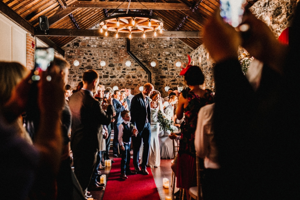 bride and groom waking out of the wedding barn after the ceremony