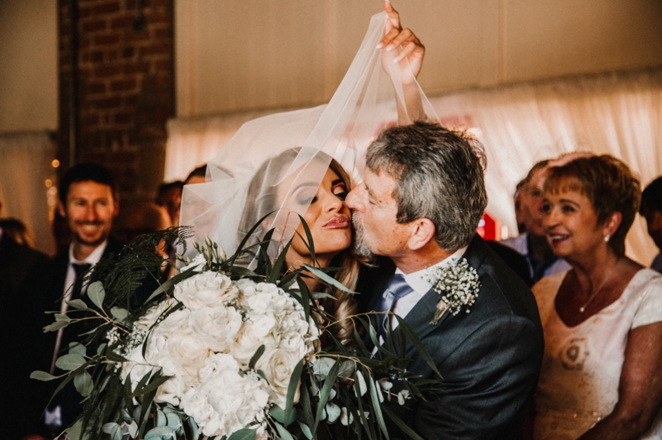 brides father lifting the veil and kissing brides cheek