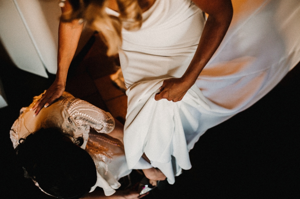 bridesmaid helping the bride get into her shoes