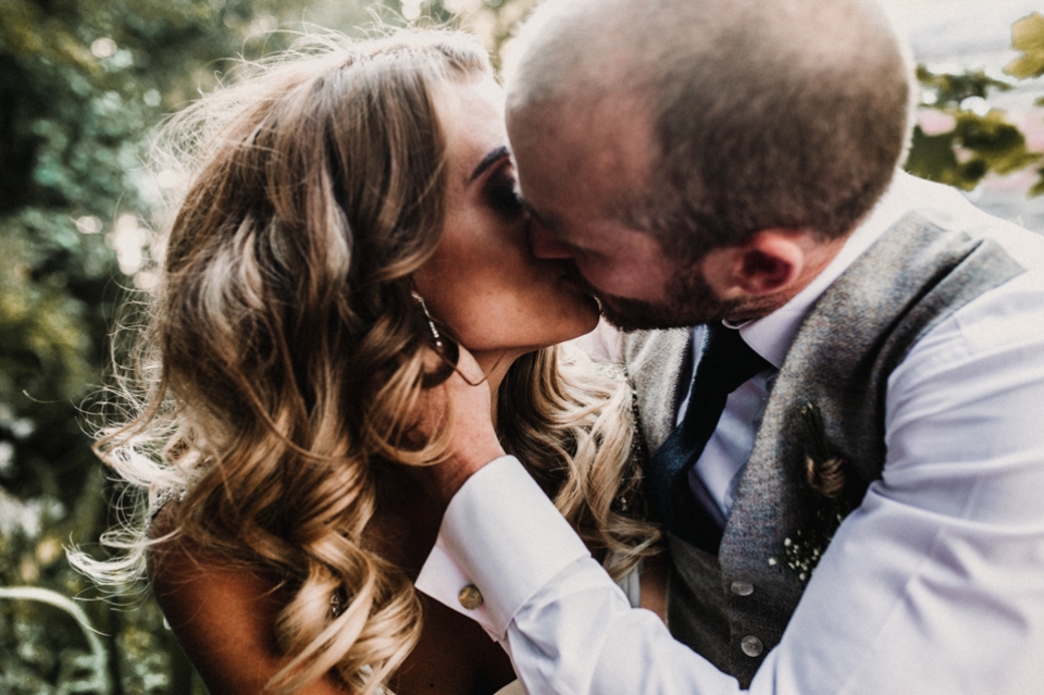 bride and groom kissing now the fence near the riverdale wedding venue lake