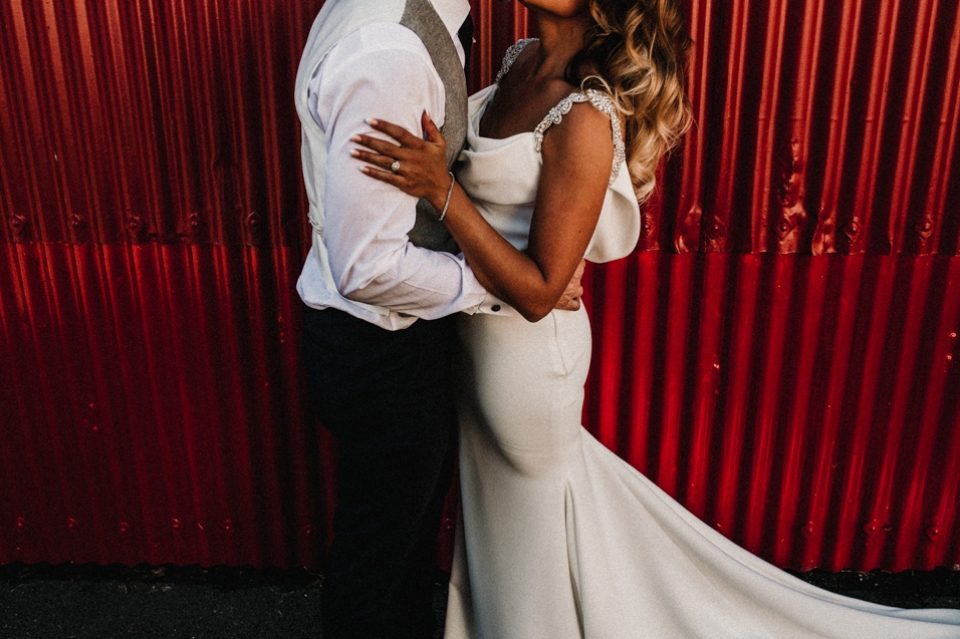 bride and groom kissing in front of the red barn at Riverdale wedding venue