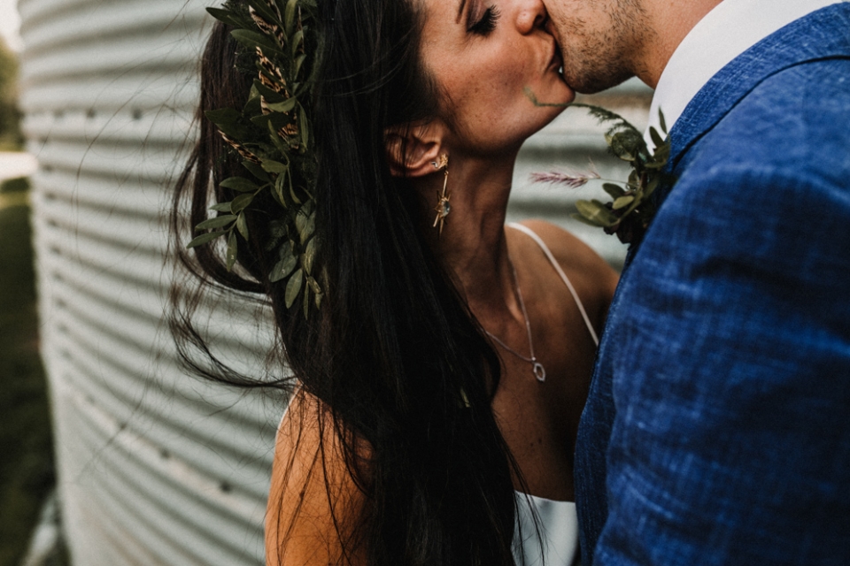 close up of bridge and groom kissing next to a barn container at Merris court