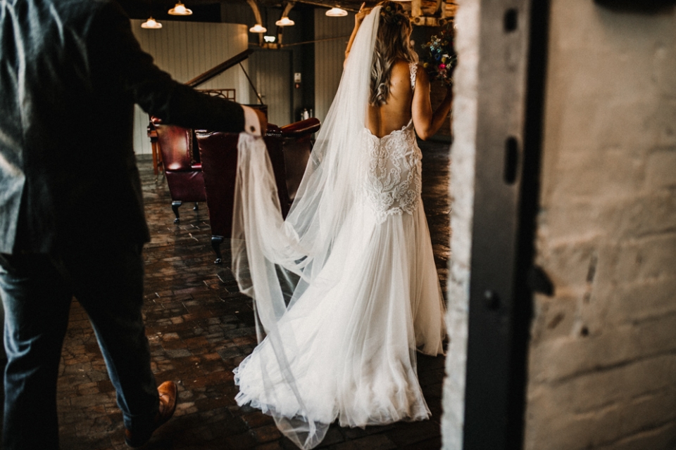 groomheping wife with her dress at the stairs in west mill wedding venue