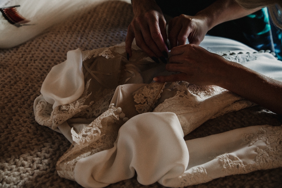 bride and mother of bride doing buttons on pronovias wedding dress