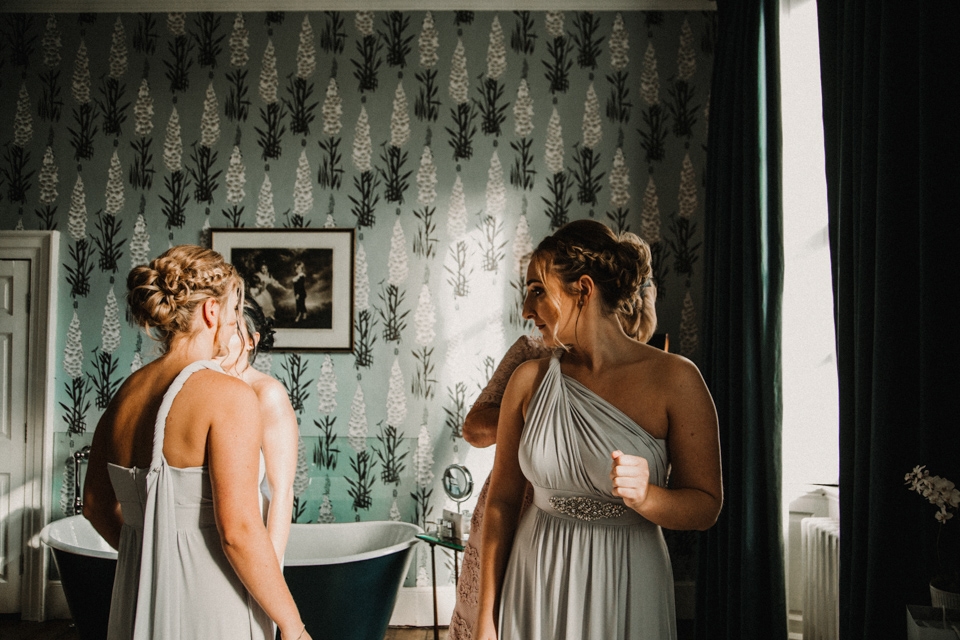 bridesmaids looking in mirror in their dresses