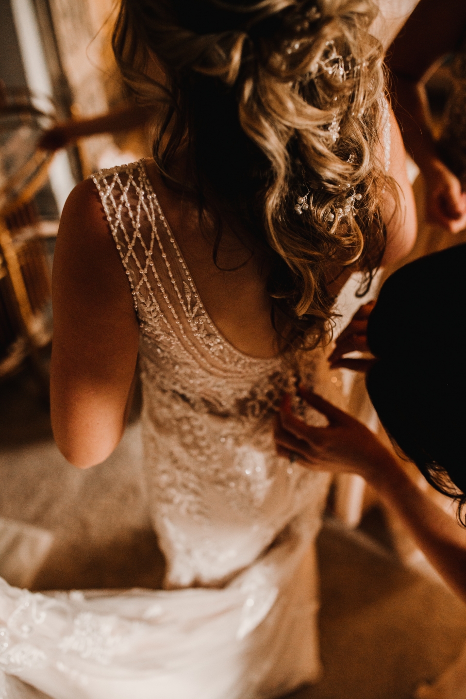 bridesmaids doing up brides dress