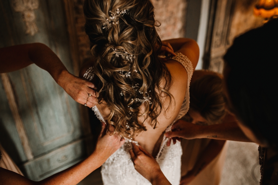 bridesmaids helping bride step into her wedding dress