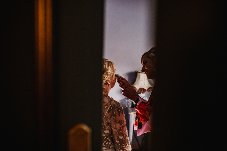 bridesmaids putting mother of the brides makeup on at bridal prep