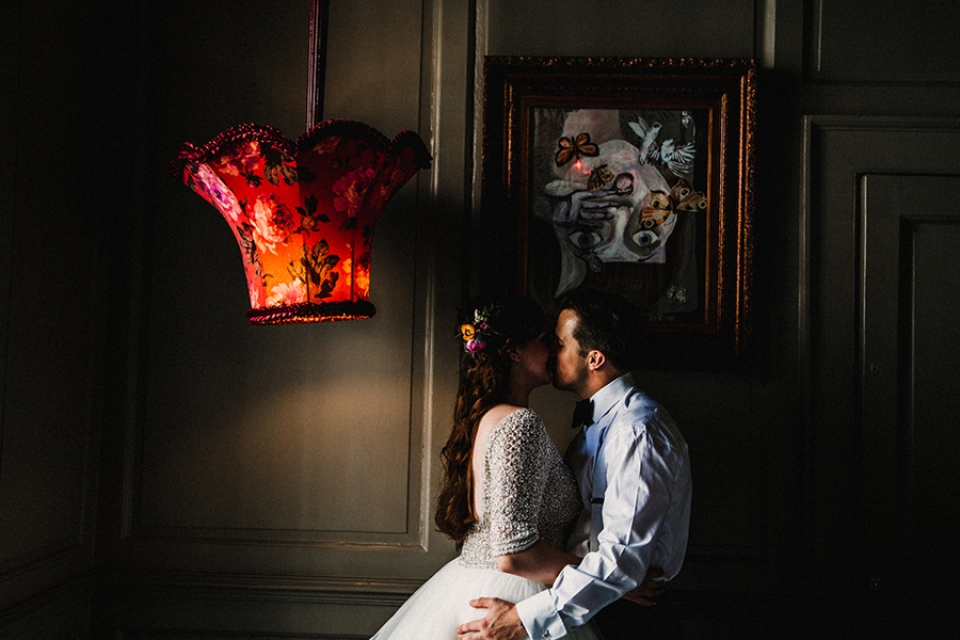 bride and groom having a kiss in the alice and wonderland themed room.