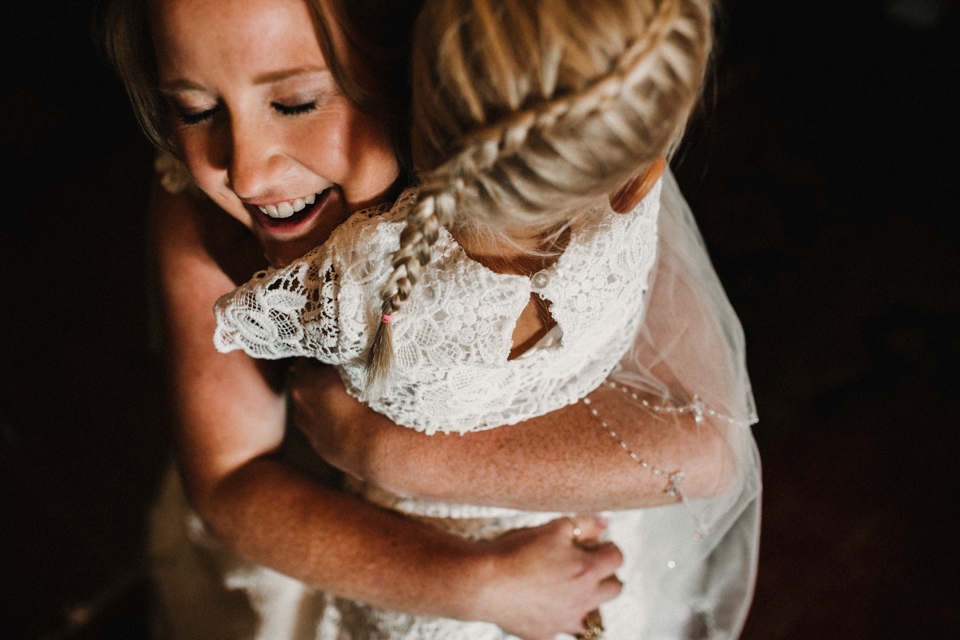 bride giving the flower girl a hug 