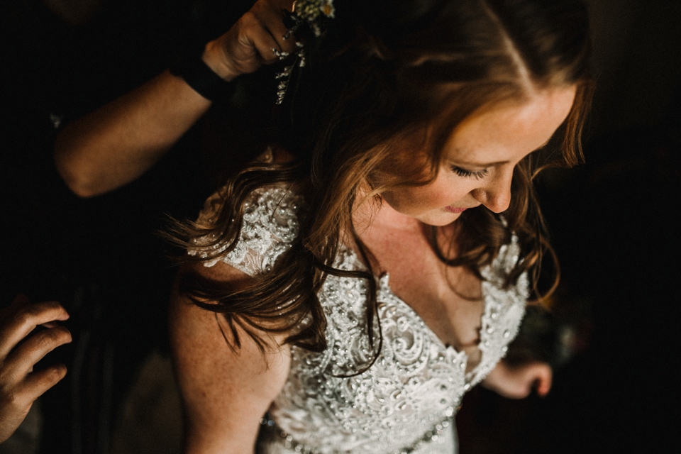 bride dressing into her wedding gown