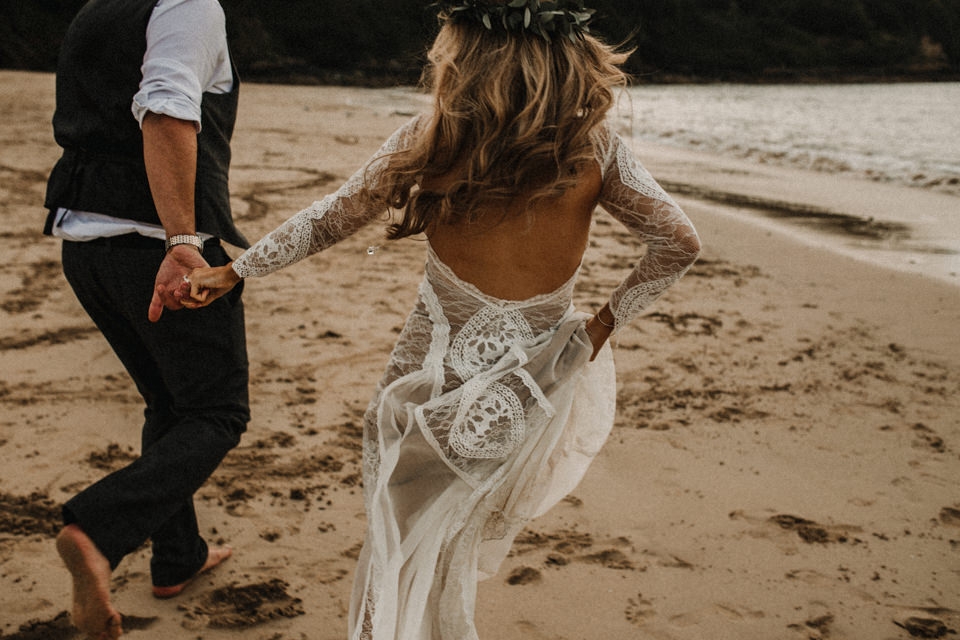 bride and groom running on the beach , playing in the water in cornwall