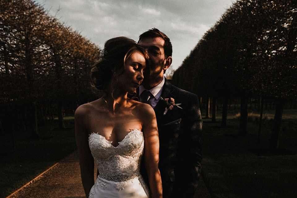 dappled sun light at sunset through the trees while bride and groom enjoy a cuddle at their combermere wedding venue