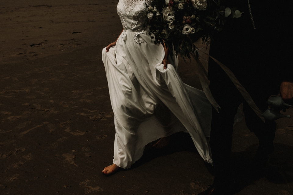 bride walking barefoot in the sand 