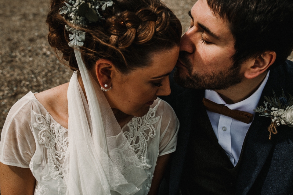 bride and groom sitting down on the beach 