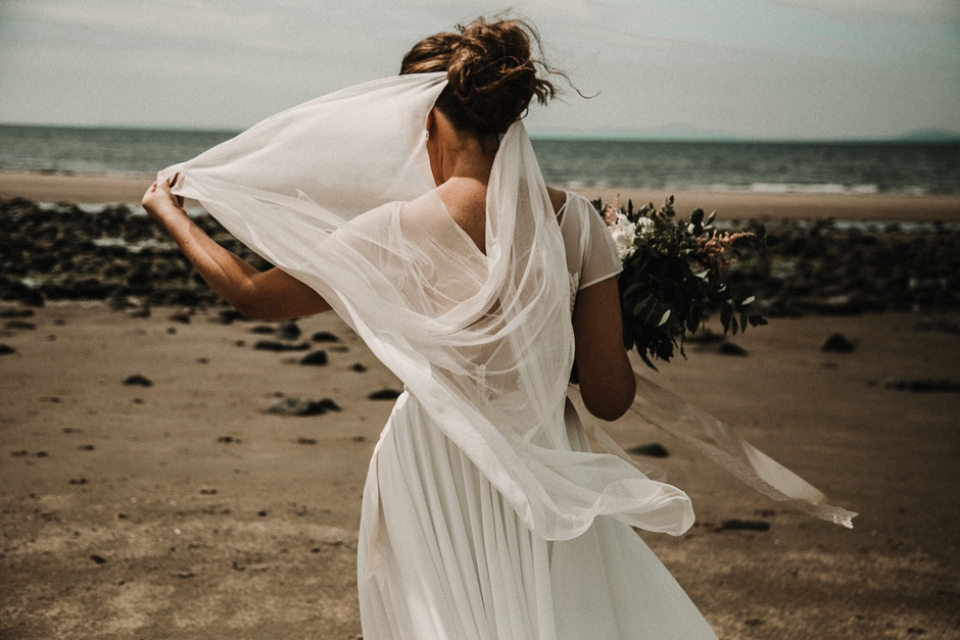 bride playing with her veil on the beach 