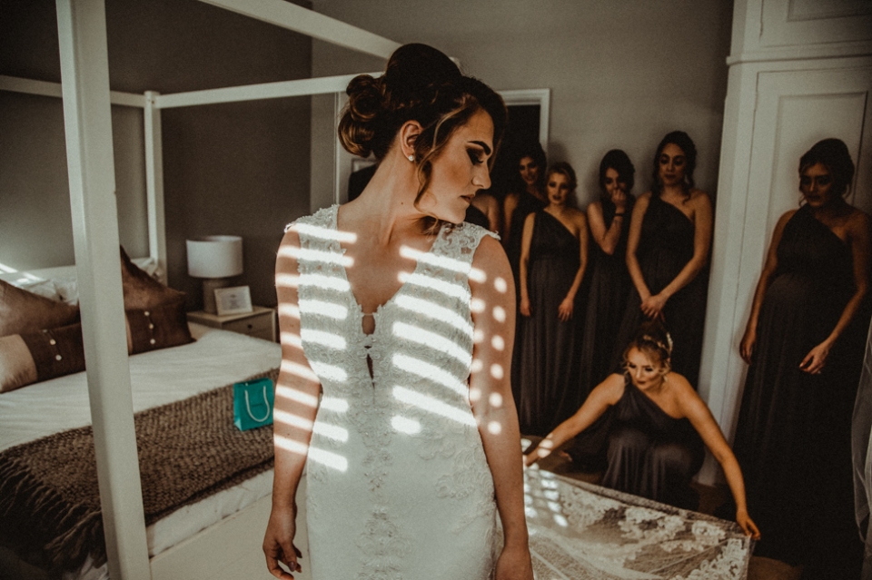 bridesmaids displaying brides wedding dress in the prep room