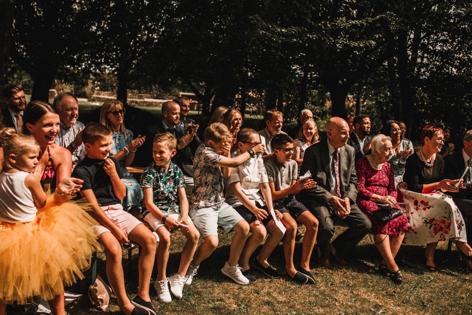 children hiding their faces at bride and grooms first kiss