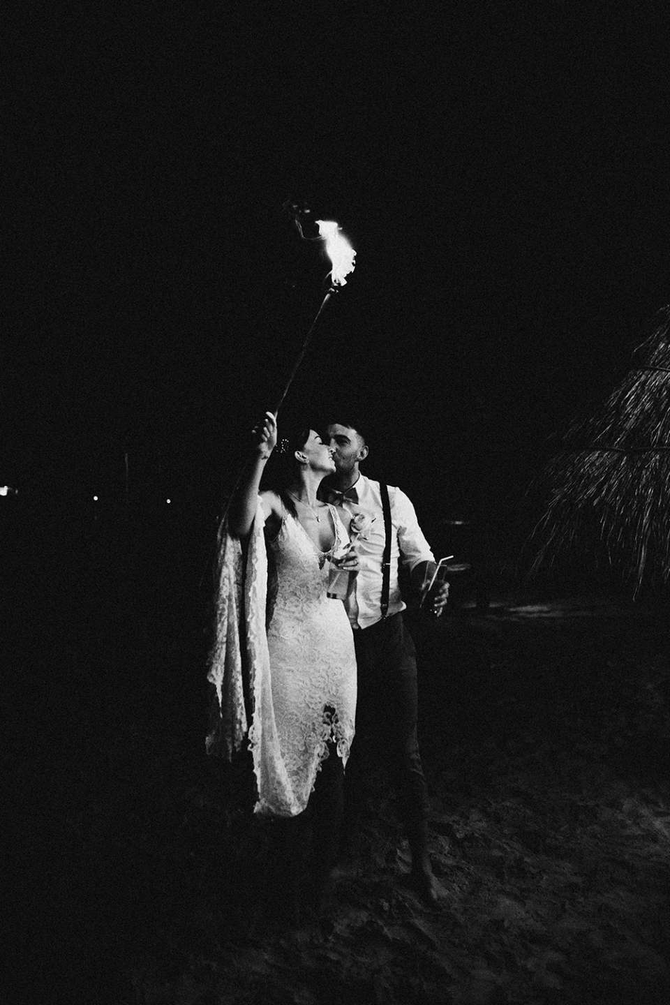 bride and groom holding sparklers on beach