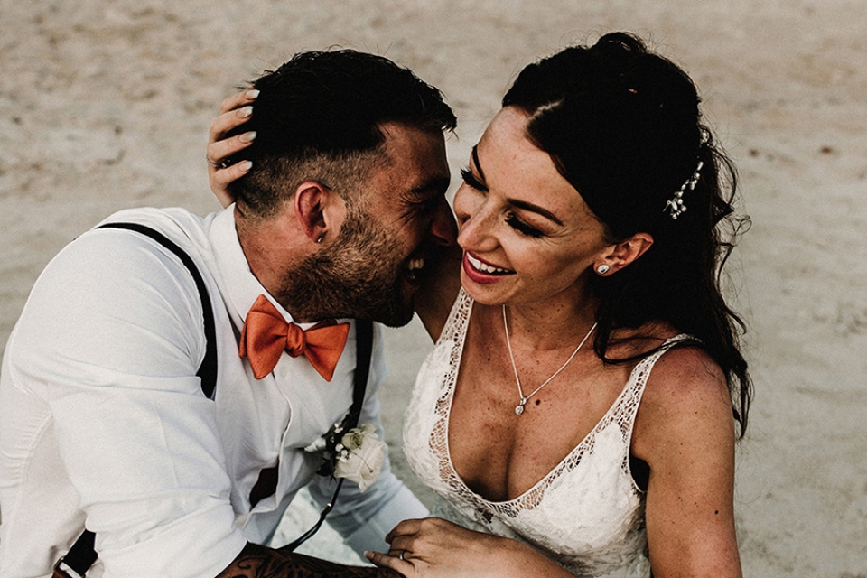 bride and groom cuddling up on the sand