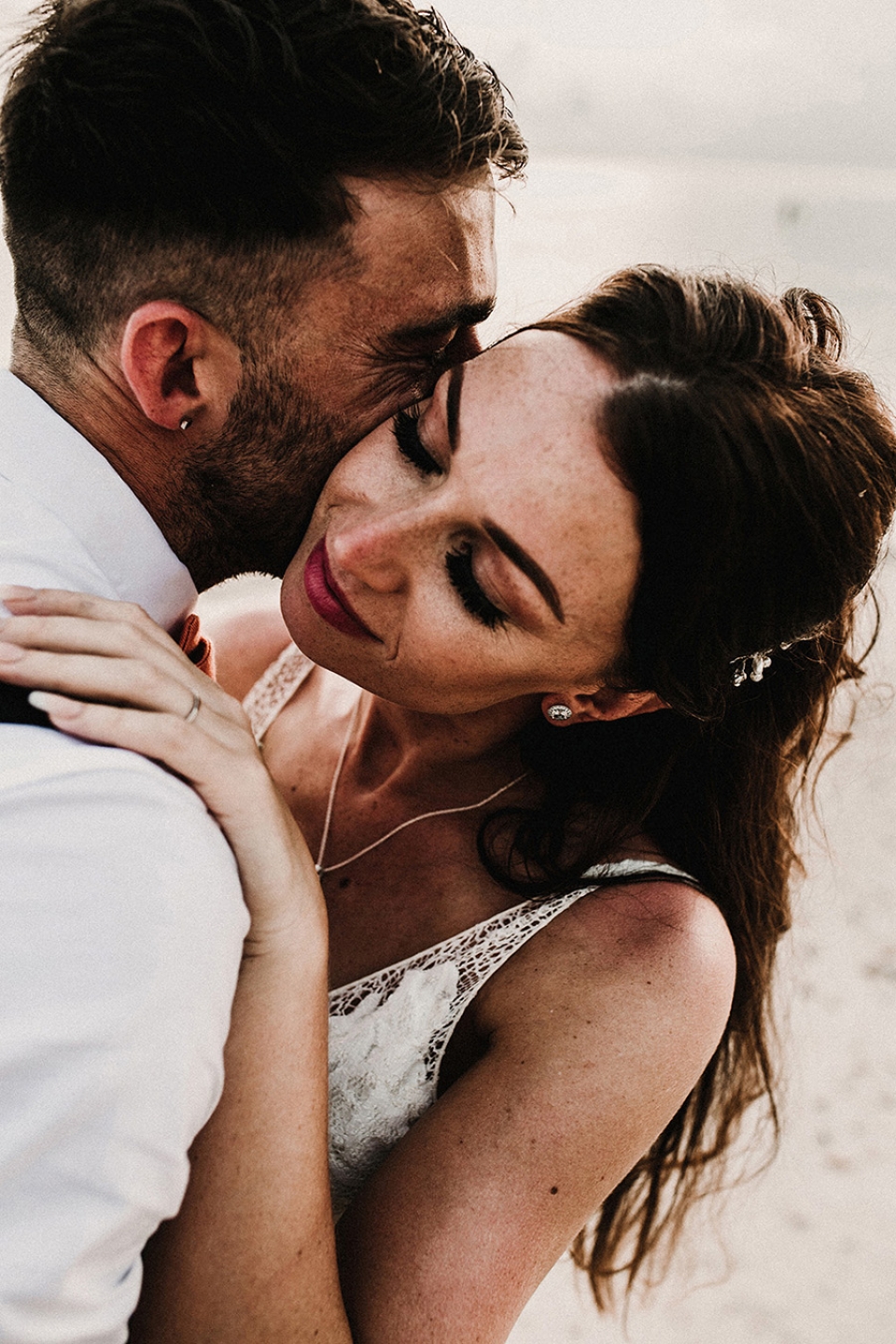 close up of bride hugging her new husband on the beach