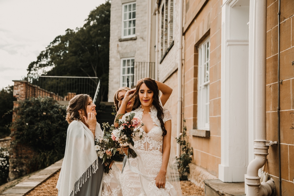 bridesmaids helping bride touch up her hair 