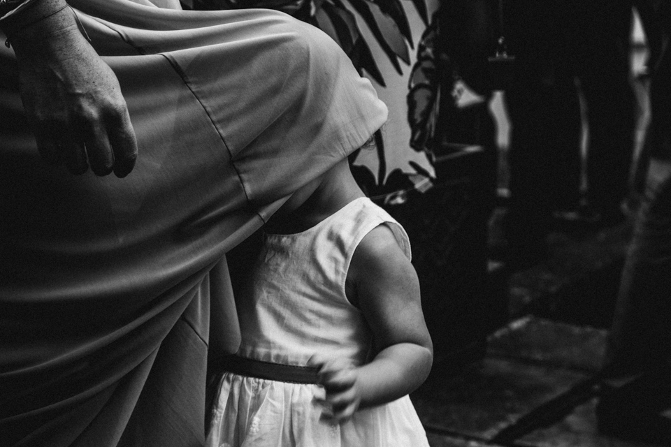 flower girl hiding under mummies dress