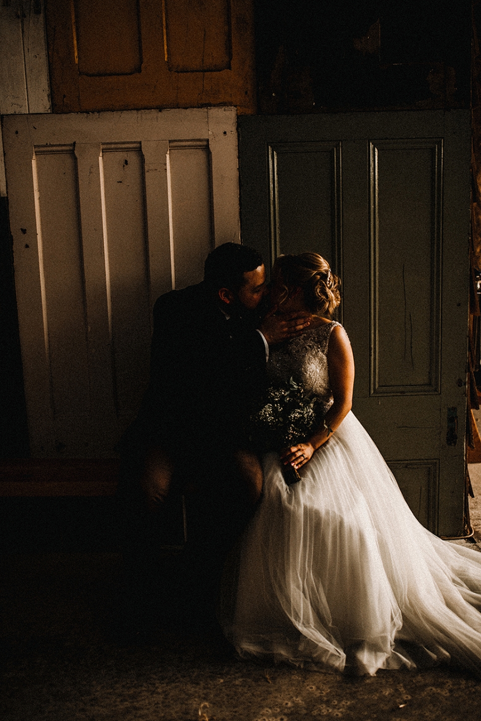 bride and groom kissing on bench in front of some cool door arty backdrop