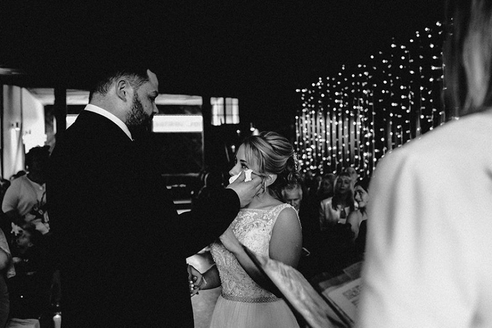 groom wiping tear from brides eyes during ceremony