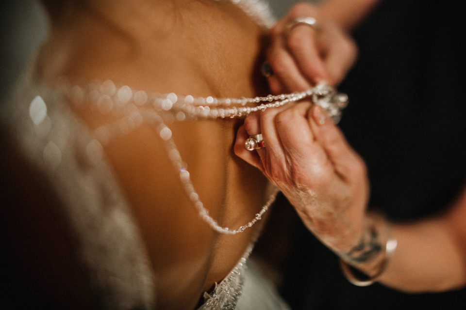 mother of the bride helping bride into her wedding gown.