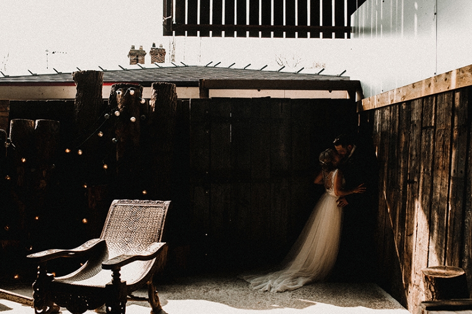 bride and groom having a kiss in the corner of the wedding barn