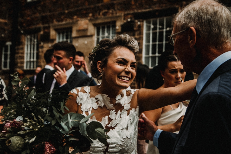 bride embracing her father on their wedding day while he congratulates her.